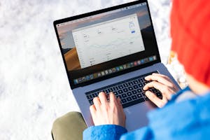A person in a blue jacket analyzing business analytics on a laptop outdoors during winter.